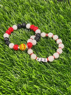 two bracelets sitting in the grass on top of each other with numbers and beads