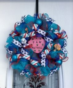 a blue and red wreath with paw patrol written on it's side hanging from the front door