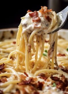 a fork full of spaghetti with bacon and cream sauce