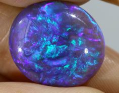 a close up of a person's hand holding a purple and blue opalite