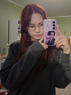 a woman taking a selfie with her cell phone in front of her and wearing glasses