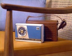 an old fashioned radio sitting on top of a wooden chair next to a blue pillow