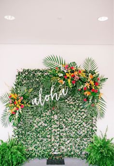 the wedding sign is surrounded by greenery and tropical flowers, which are arranged on top of each other