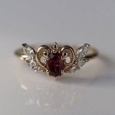 a close up of a ring on a white surface with a red stone in the middle