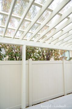 a white pergolated roof with trees in the background