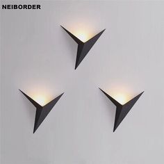 three modern wall lights in the shape of triangulars on a white wall with dim lighting