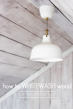 two white lamps hanging from the ceiling in a room with wood paneling and planked walls