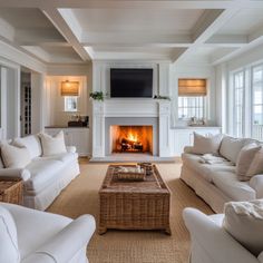 a living room filled with white furniture and a fire place in the middle of it