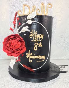 a black and gold birthday cake with a red rose on top that says happy 8th anniversary