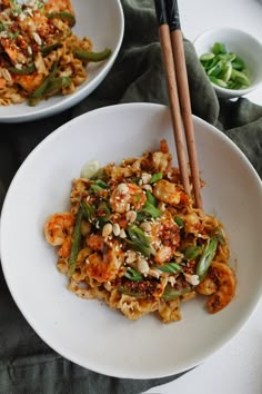 two white plates filled with food and chopsticks next to each other on a table