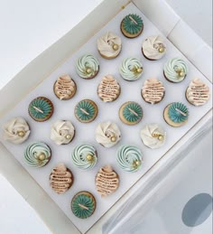 cupcakes are displayed in a white box with gold trim and blue frosting