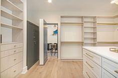 an empty walk in closet with white cabinets