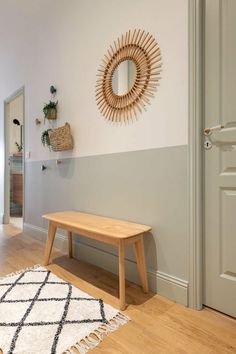 a wooden bench sitting in front of a mirror on the wall next to a door