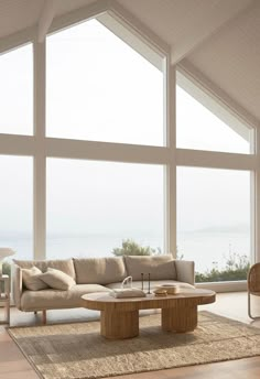 a living room filled with lots of furniture next to large windows on top of a wooden floor