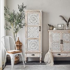 a white cabinet sitting next to a chair in a living room on top of a rug