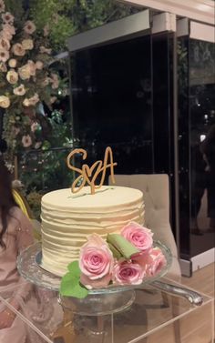 a woman sitting in front of a cake with flowers on the table next to it