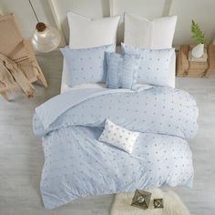 a bed with blue sheets and pillows in a room next to a white rug on the floor