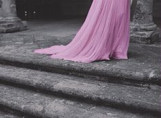 a woman in a pink dress standing on some steps with her back to the camera