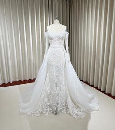 a white wedding dress on display in front of curtains