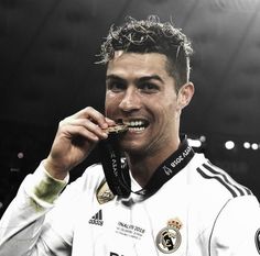 a male soccer player holding a medal in his right hand and smiling at the camera