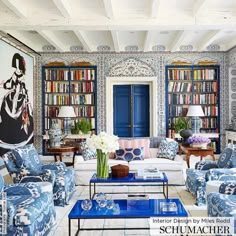 a living room filled with furniture and bookshelves covered in blue and white wallpaper