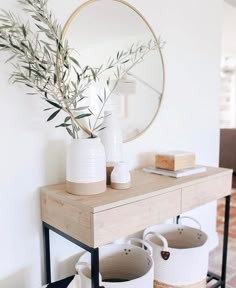 a table with two vases on it and a mirror in the corner behind it