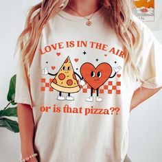 a woman wearing a t - shirt that says love is in the air or is that pizza?