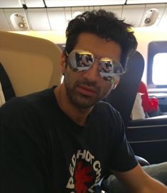 a man wearing mirrored sunglasses on an airplane