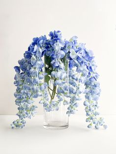 a glass vase filled with blue flowers on top of a table