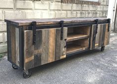 a wooden entertainment center with metal handles and wheels on the outside of a brick building