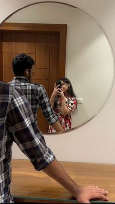 a man and woman taking a photo in front of a mirror with their cell phones