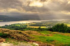 the sun shines through clouds over a valley and lake