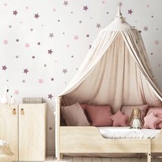 a child's bedroom with pink stars on the wall and white bed canopy over it