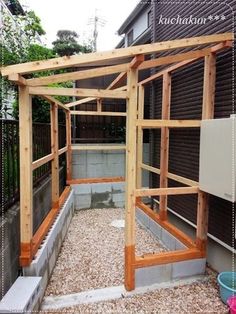 an outdoor chicken coop built into the side of a house with wooden posts and wood slats