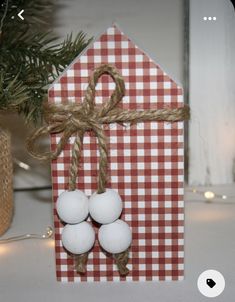 an ornament with three white balls tied to it, sitting in front of a christmas tree