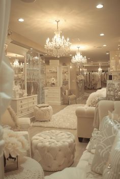 a room filled with lots of white furniture and chandelier hanging from the ceiling