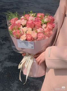 a woman holding a bouquet of pink roses