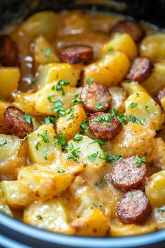 a bowl filled with potatoes and sausage covered in gravy, garnished with parsley