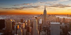 an aerial view of the new york city skyline at sunset, with skyscrapers in the foreground