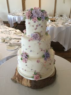 a three tiered wedding cake sitting on top of a wooden slice at a table