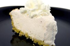 a piece of pie with whipped cream on top is sitting on a black plate, ready to be eaten