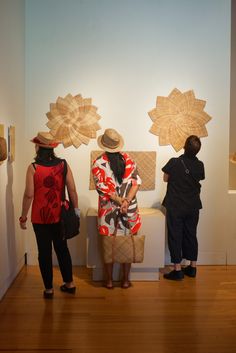 three people looking at artwork on the wall