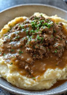 mashed potatoes topped with meat and gravy in a bowl on a table