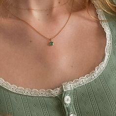 a woman wearing a necklace with a green stone