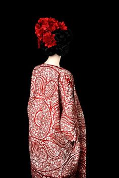 the back of a woman's head with red flowers in her hair and dress