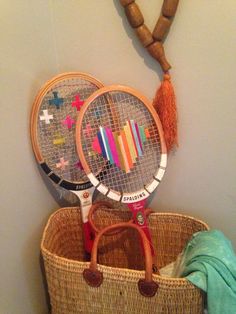 two tennis racquets are in a basket next to a necklace on a wall