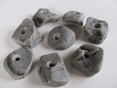 several gray rocks sitting on top of a white table next to each other, with holes in the middle