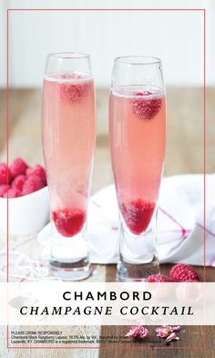 two champagne flutes filled with raspberries on a table