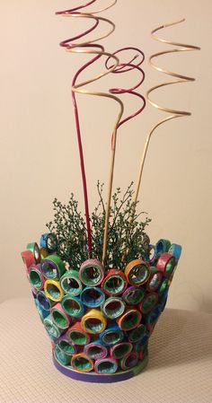 a vase filled with lots of different colored paper and some metal scissors on top of a table