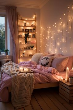 a bed with pink sheets, pillows and candles in front of a window filled with lights